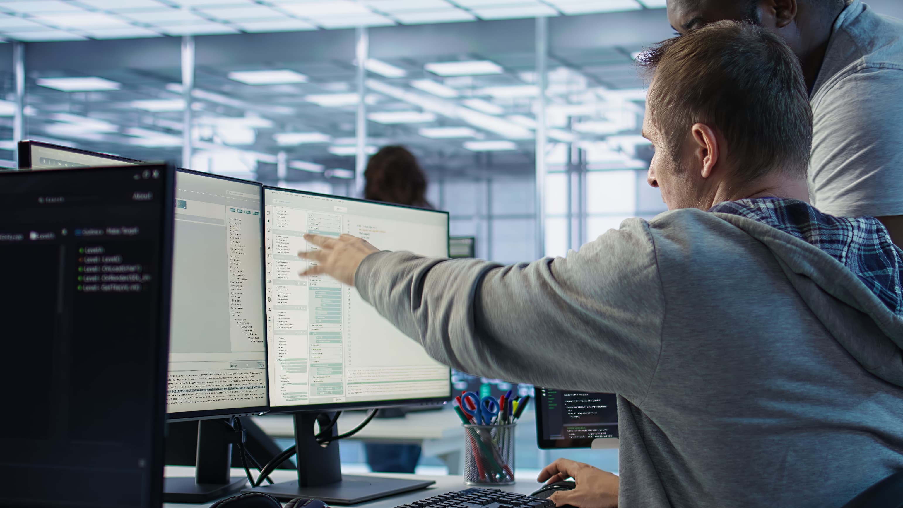 A hand pointing towards a computer monitor