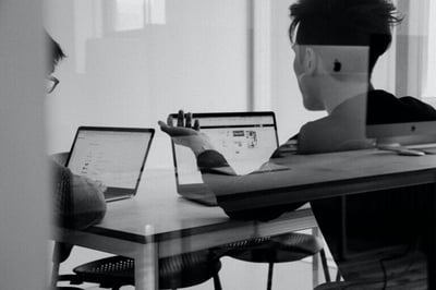 Menschen arbeiten am PC in einem Büro mit Glasfenstern