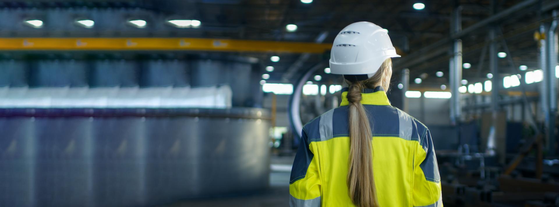 Woman standing with back towards camera in industrial environment