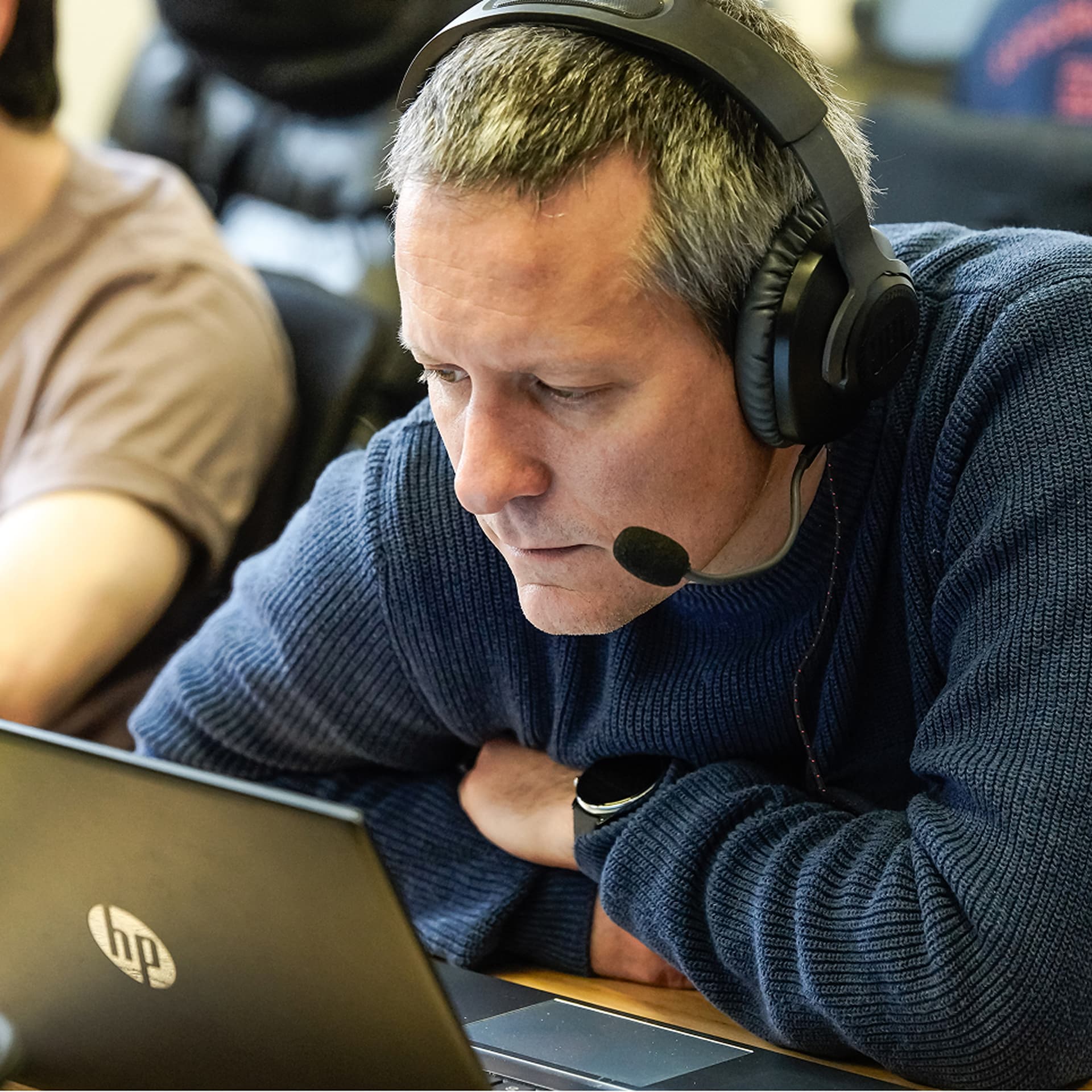 IT professional in a blue sweater using a headset and working on a laptop, focused on ServiceNow Platform features and benefits.