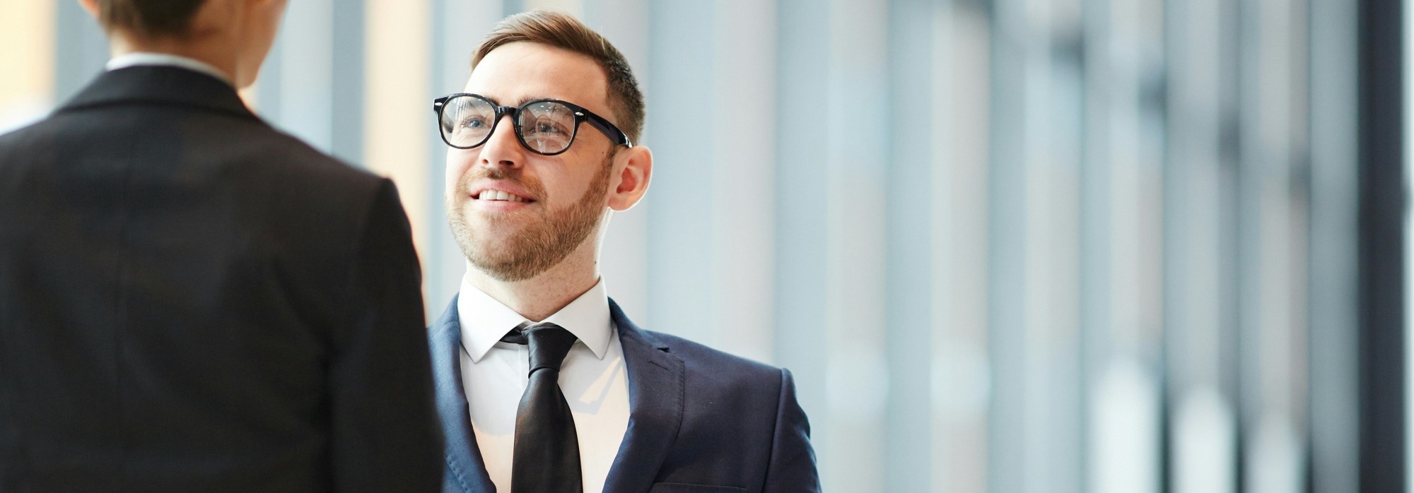 Two business professionals shaking hands in a modern office setting