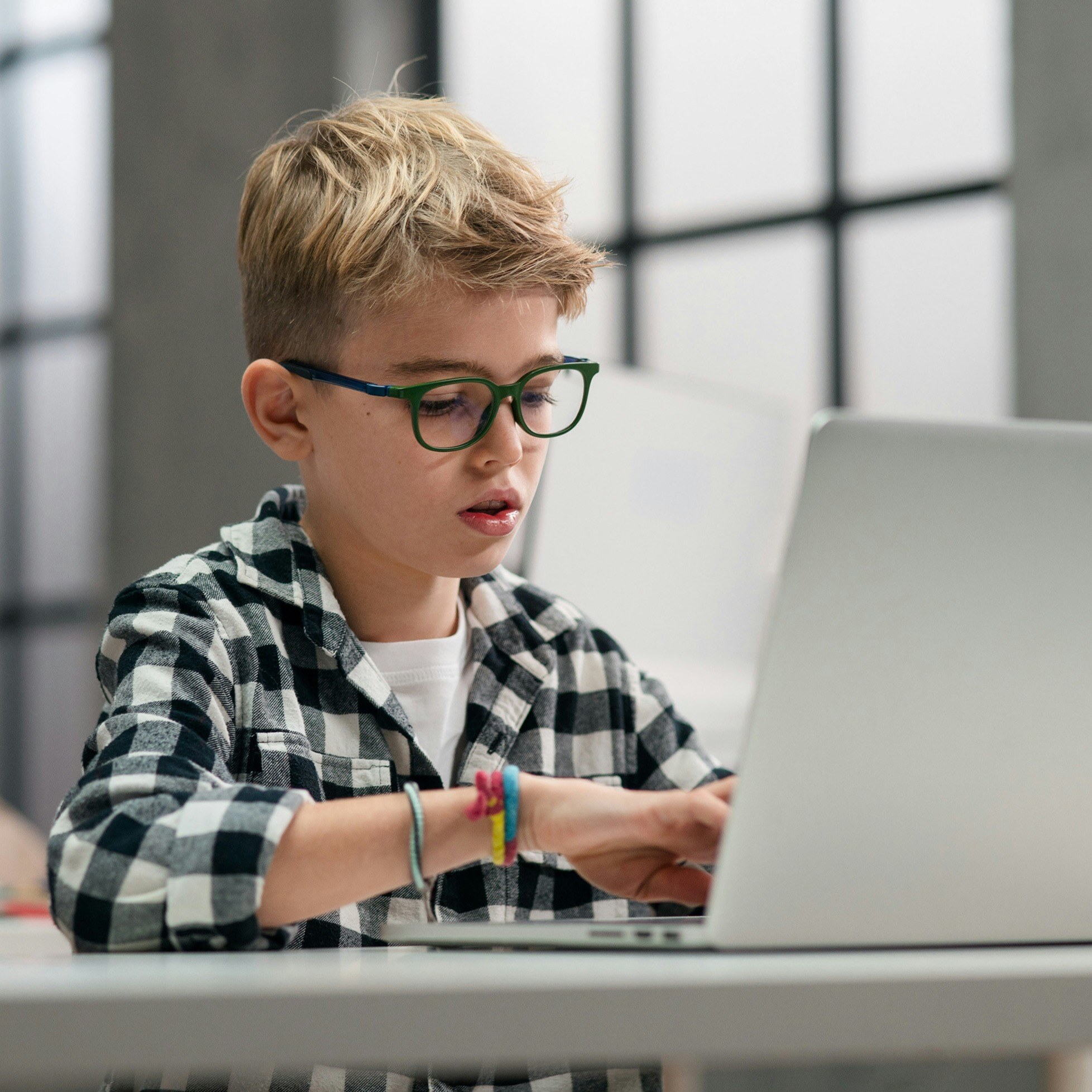 child wearing glasses looking at laptop