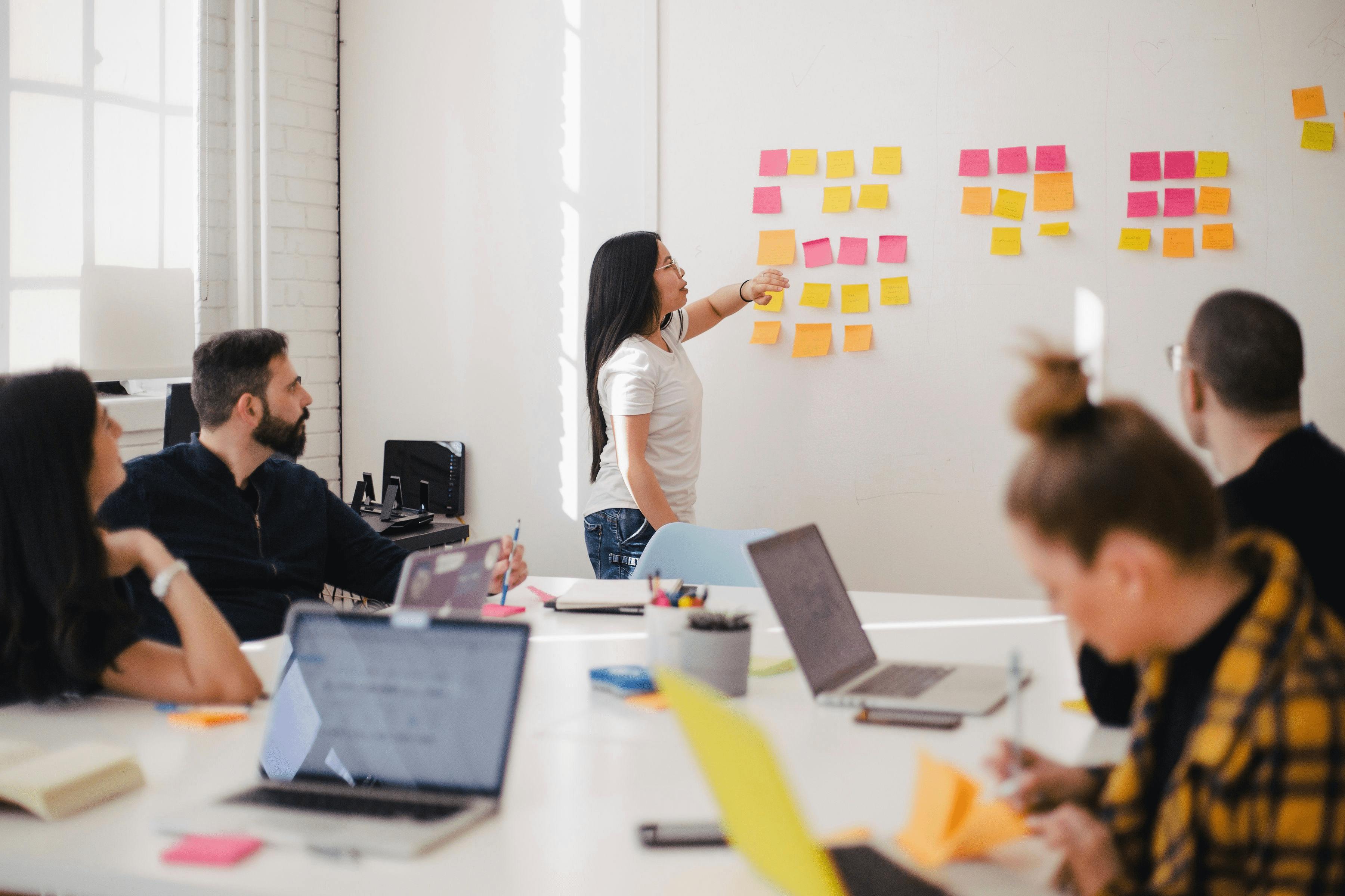 Frau zeigt auf Post-its während einer Schulung