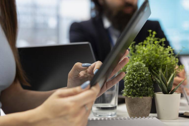 woman-reading-diagrams-tablet-device-helped-by-specialist-768x512