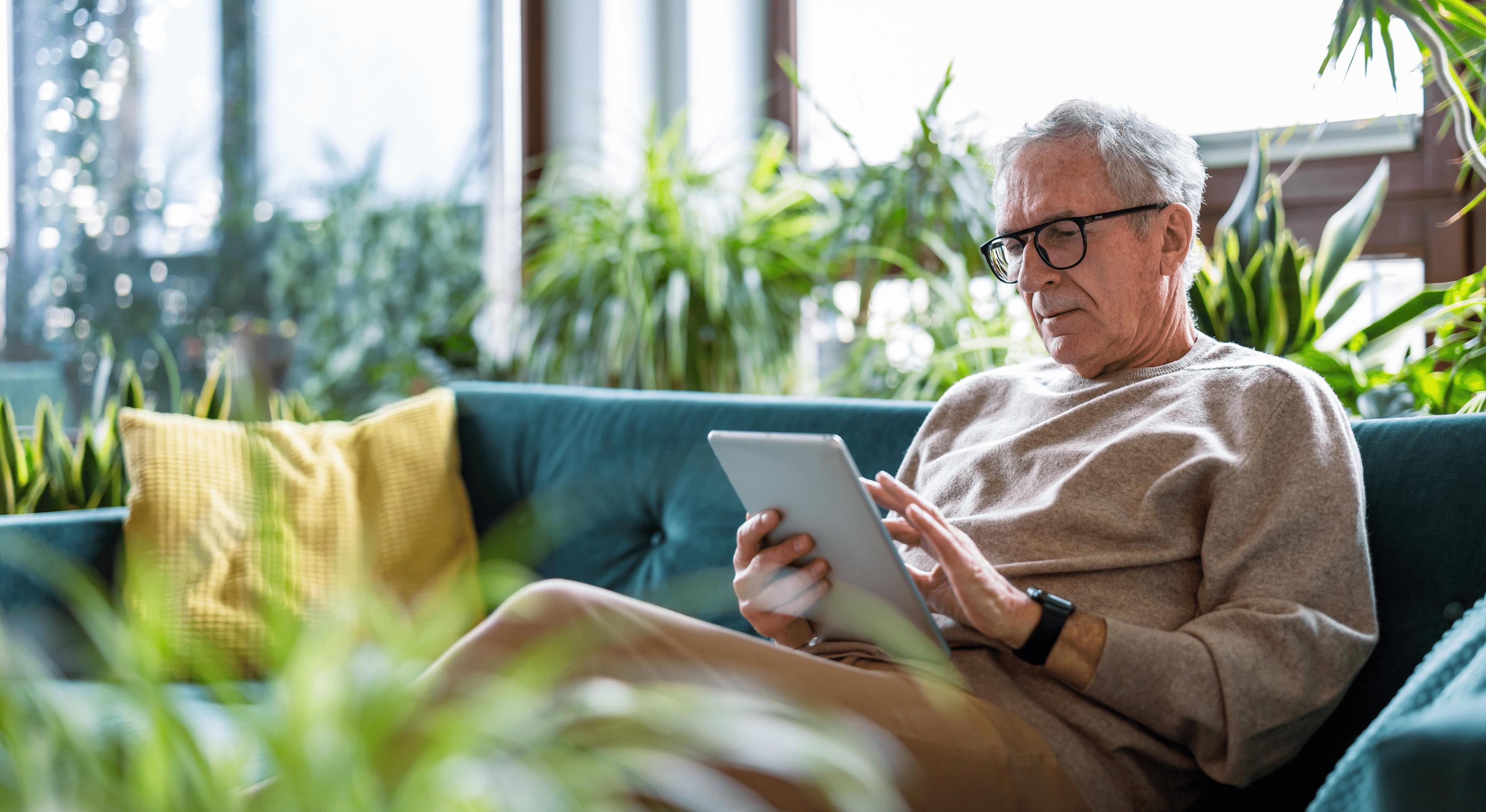 Elderly man sitting on a couch with tablet
