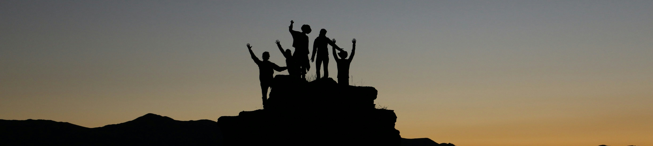 Silhouetten von Menschen auf einem Hügel bei Sonnenaufgang