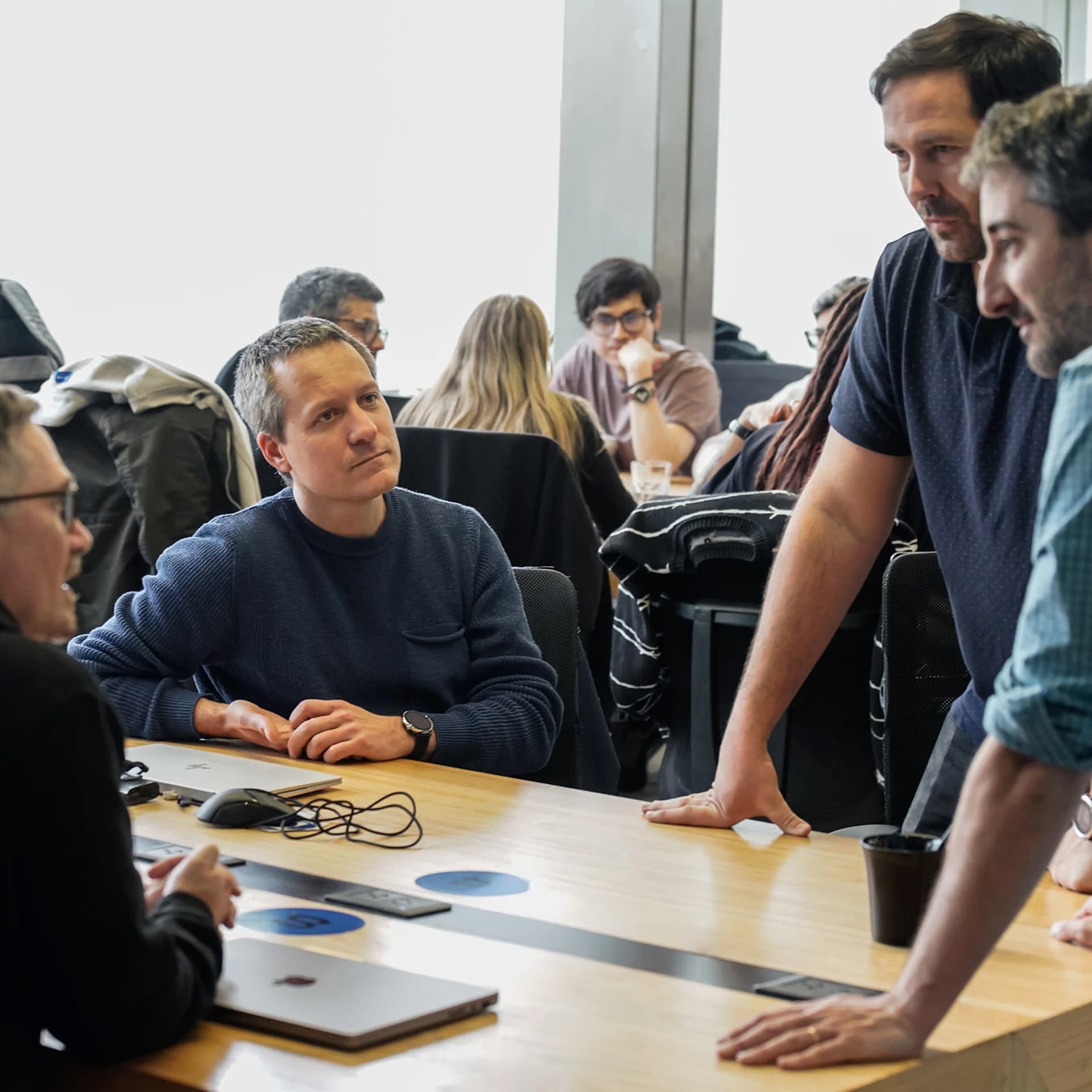 Team meeting comparing ServiceNow and Dynamics 365 business solutions on a conference table.