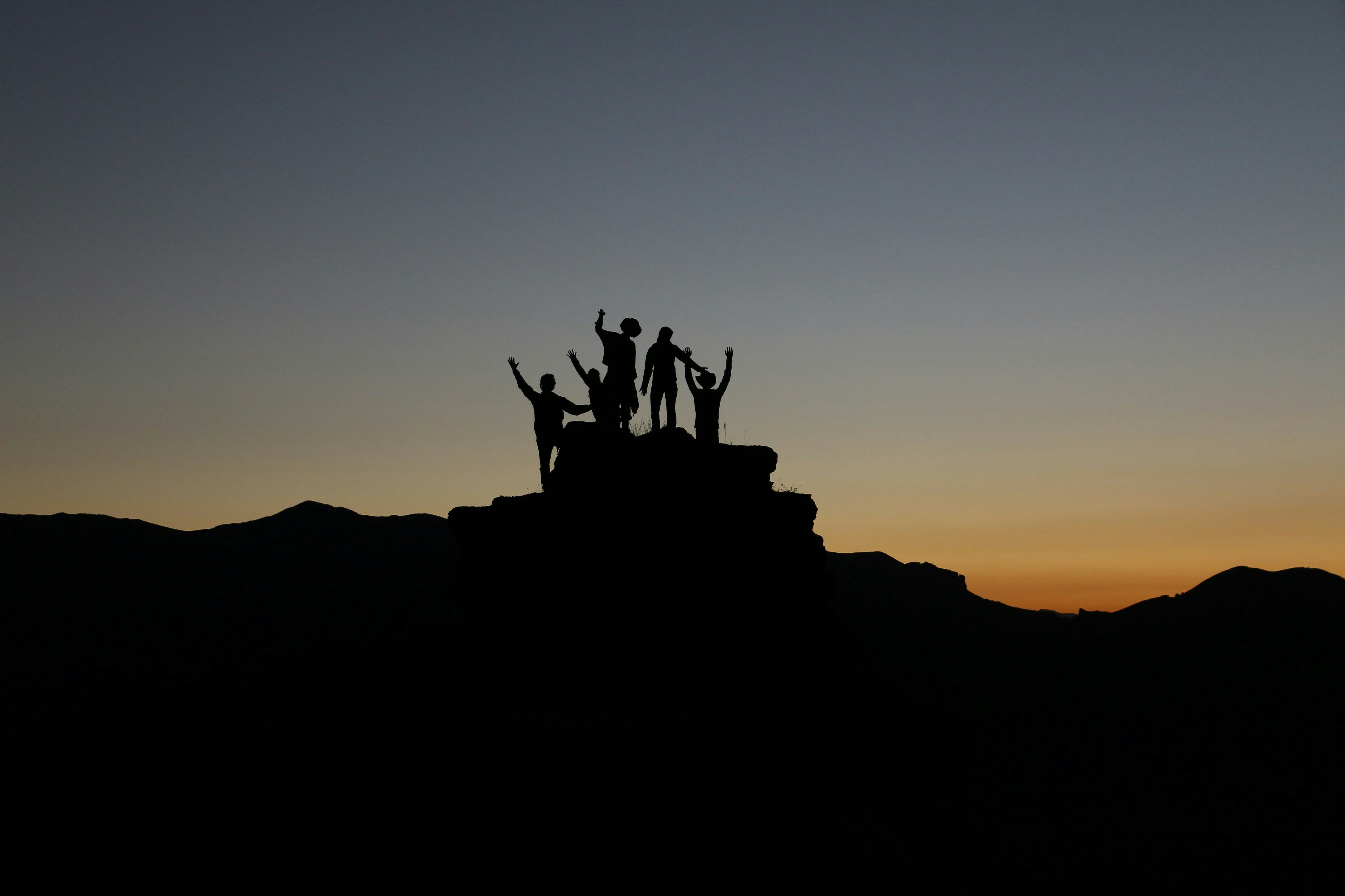 Silhouettes of People on a hill during sunrise.