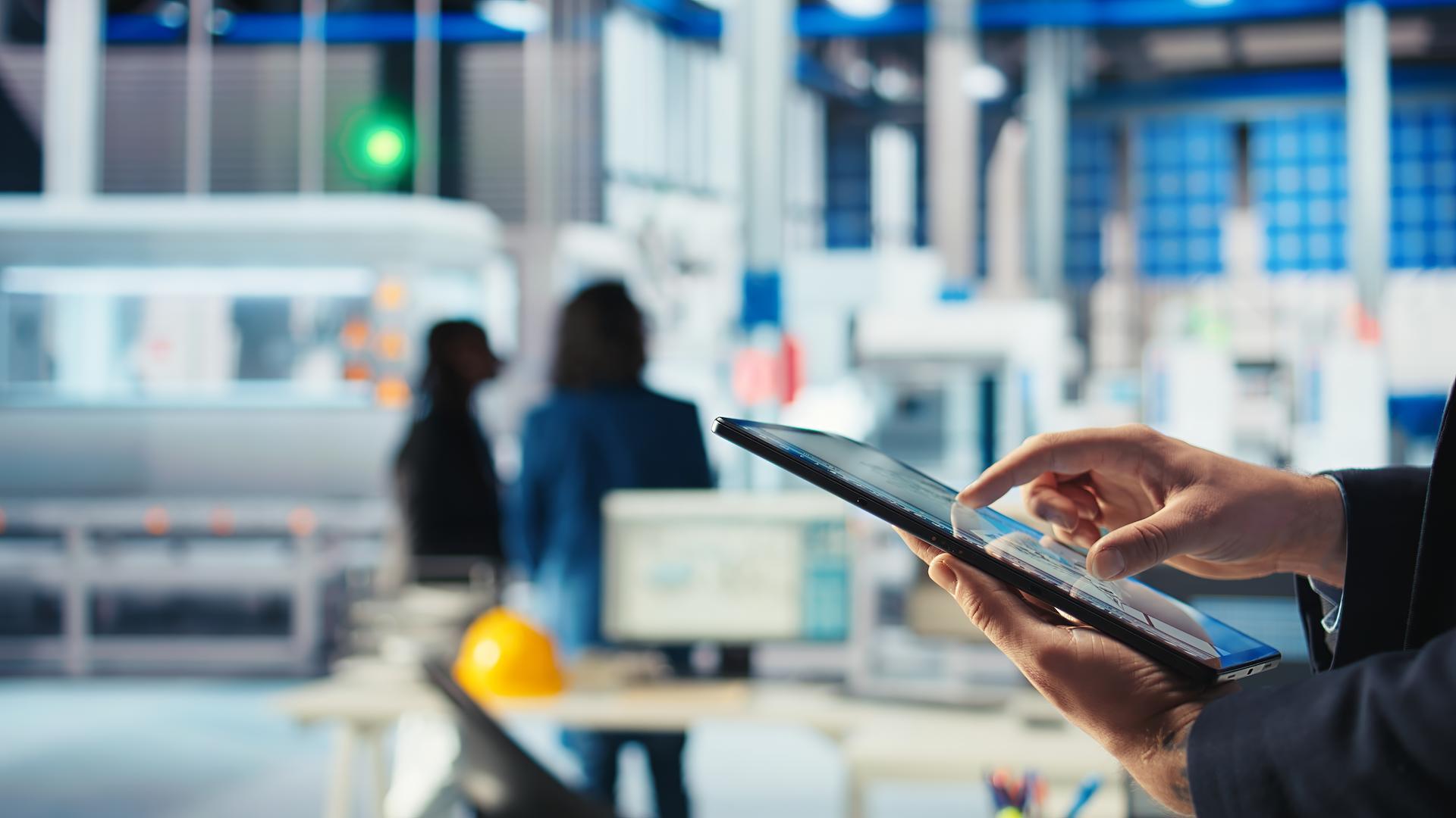 A person's hand touching a tablet and blurry background of people