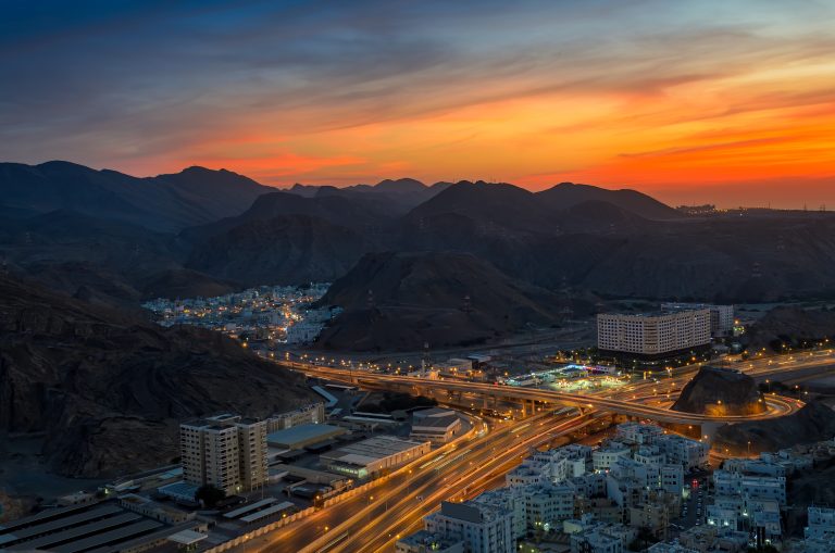 Orange sunset over Muscat city reflecting transition of Oman