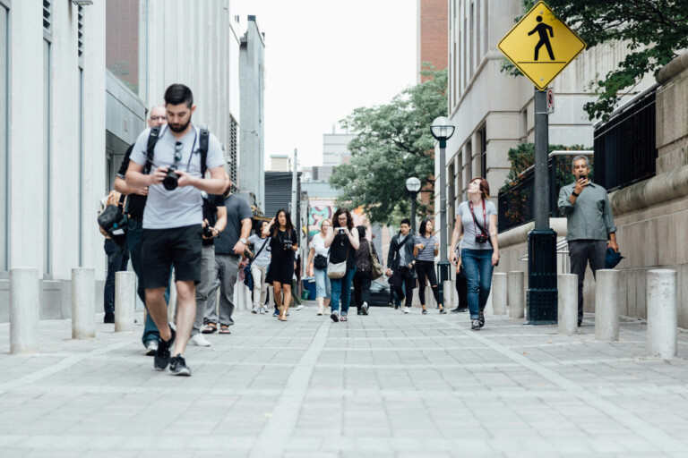 People walking on the street, some are using mobiles